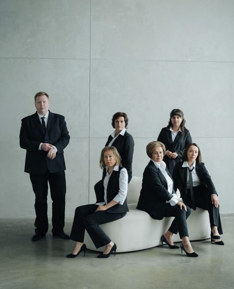 Group of business people in formal attire posing indoors