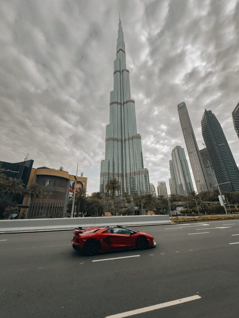 Red sports car drives past burj khalifa skyscraper